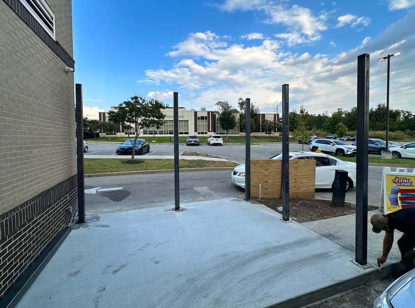 Construction site with metal poles installed on concrete foundation and clear blue sky backdrop.